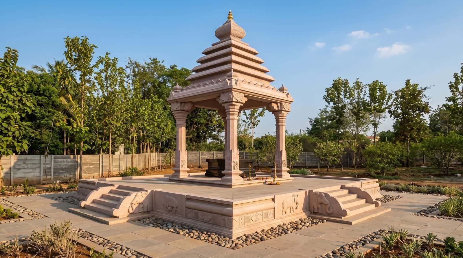 Pink granite mandapam with a tiered roof and carved elephant reliefs in a landscaped garden